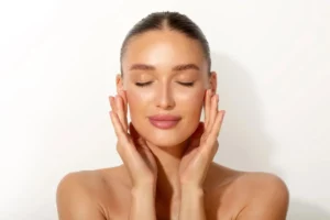 Woman with glowing skin touching face at Elko Replenish Med Spa