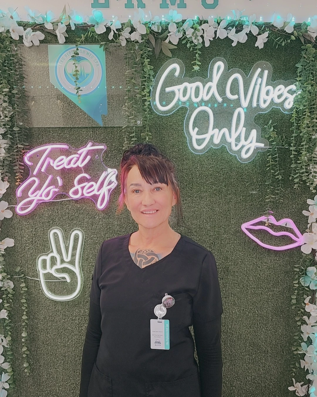 Licensed massage therapist at Elko Refresh Med Spa in Elko, Nevada, standing in front of wellness-themed neon signage.